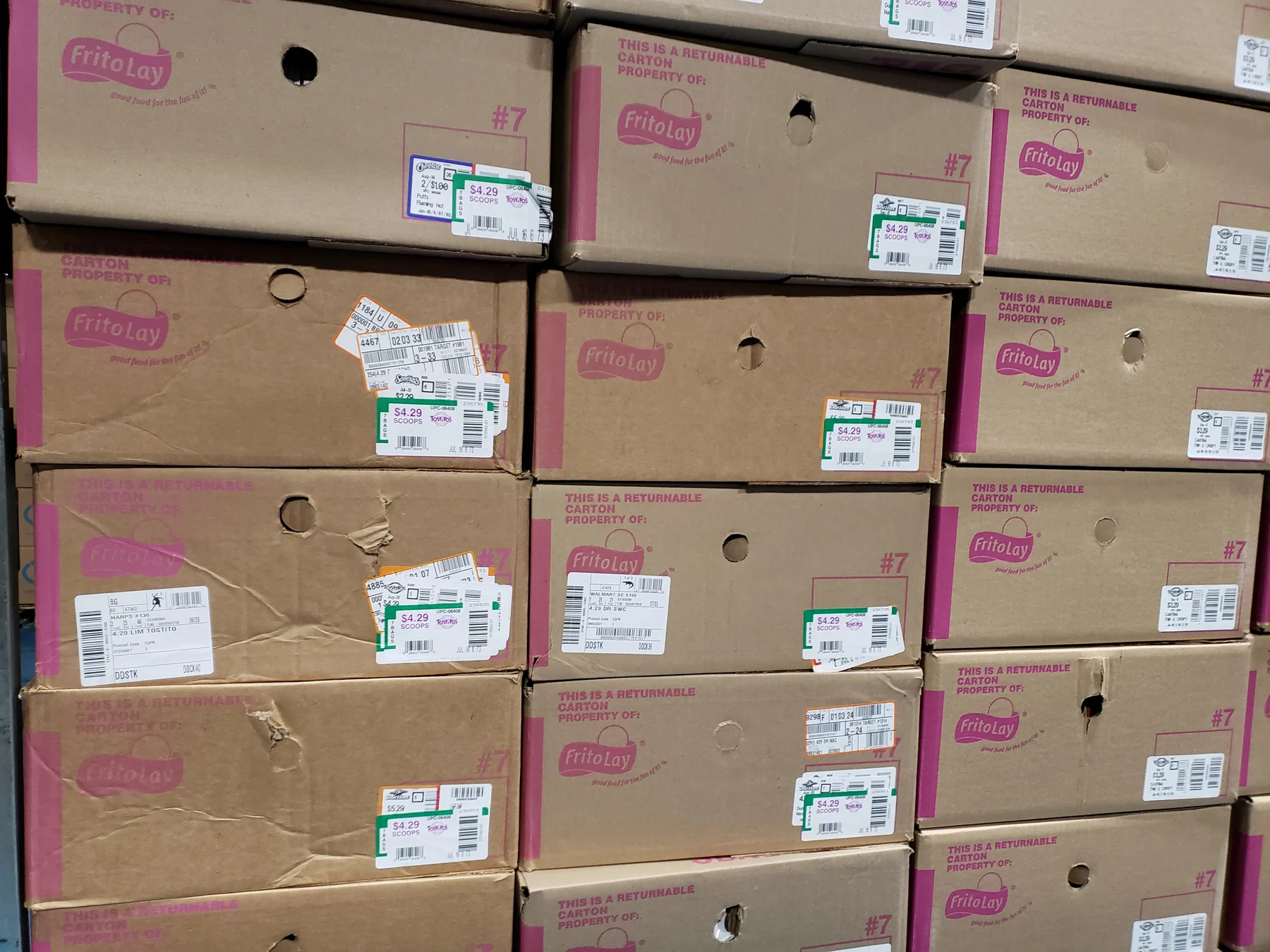 Stacked Frito-Lay cardboard cartons, each identified only by a small printed price and barcode sticker.